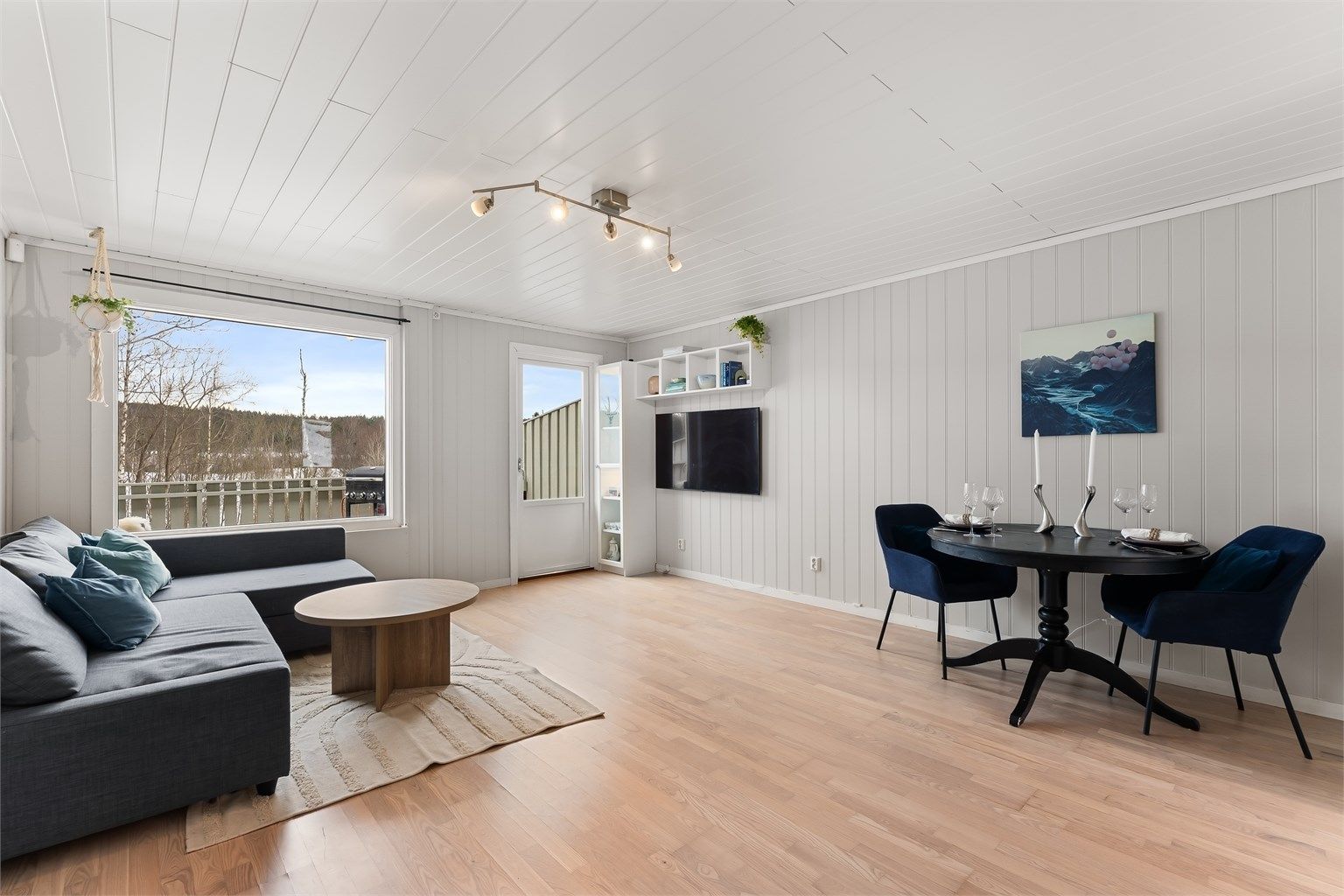 Rommet har en åpen og luftig atmosfære med gjennomgående tregulv.