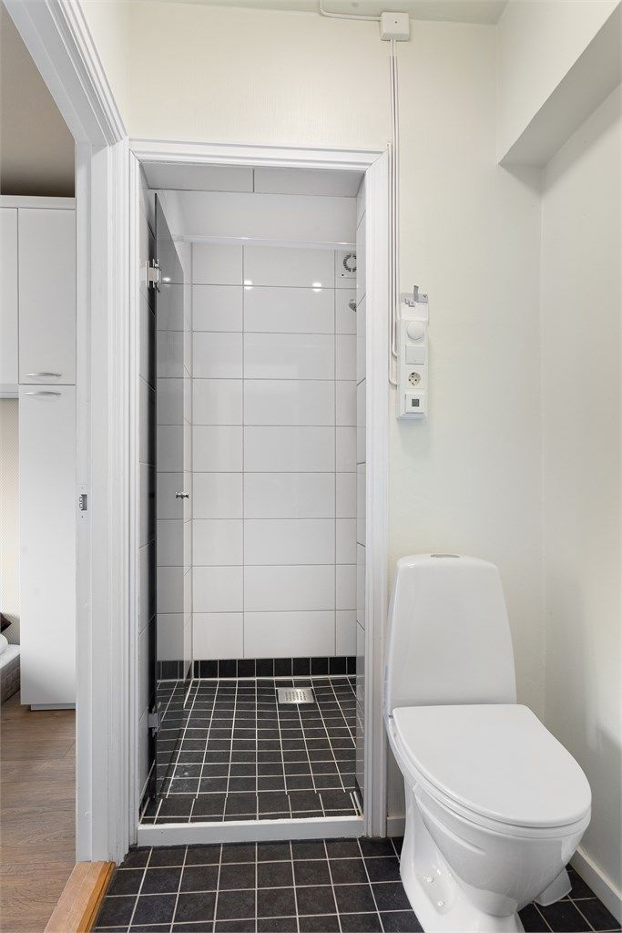 Leiligheten har et separat toalettrom i tilknytning til dusjrommet, med fliser på gulvet.