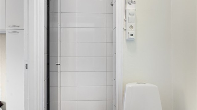 Leiligheten har et separat toalettrom i tilknytning til dusjrommet, med fliser på gulvet.