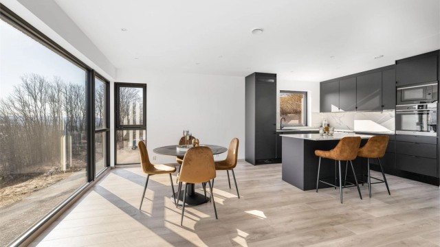 Kjøkkendelen har en pen takhøy innredning fra Systemkjøkken med sorte slette fronter, laminert benkeplate med stålvask og Kitchen Wall plater over kjøkkenbenk.