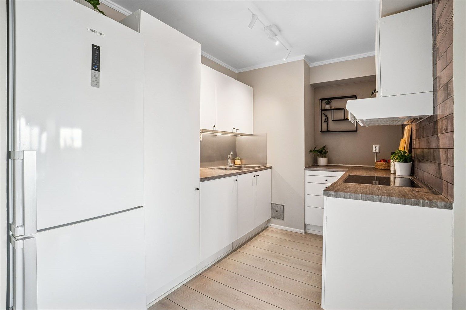 Kjøkkenet er praktisk utformet med integrerte hvitevarer og god benke- og skapplass.