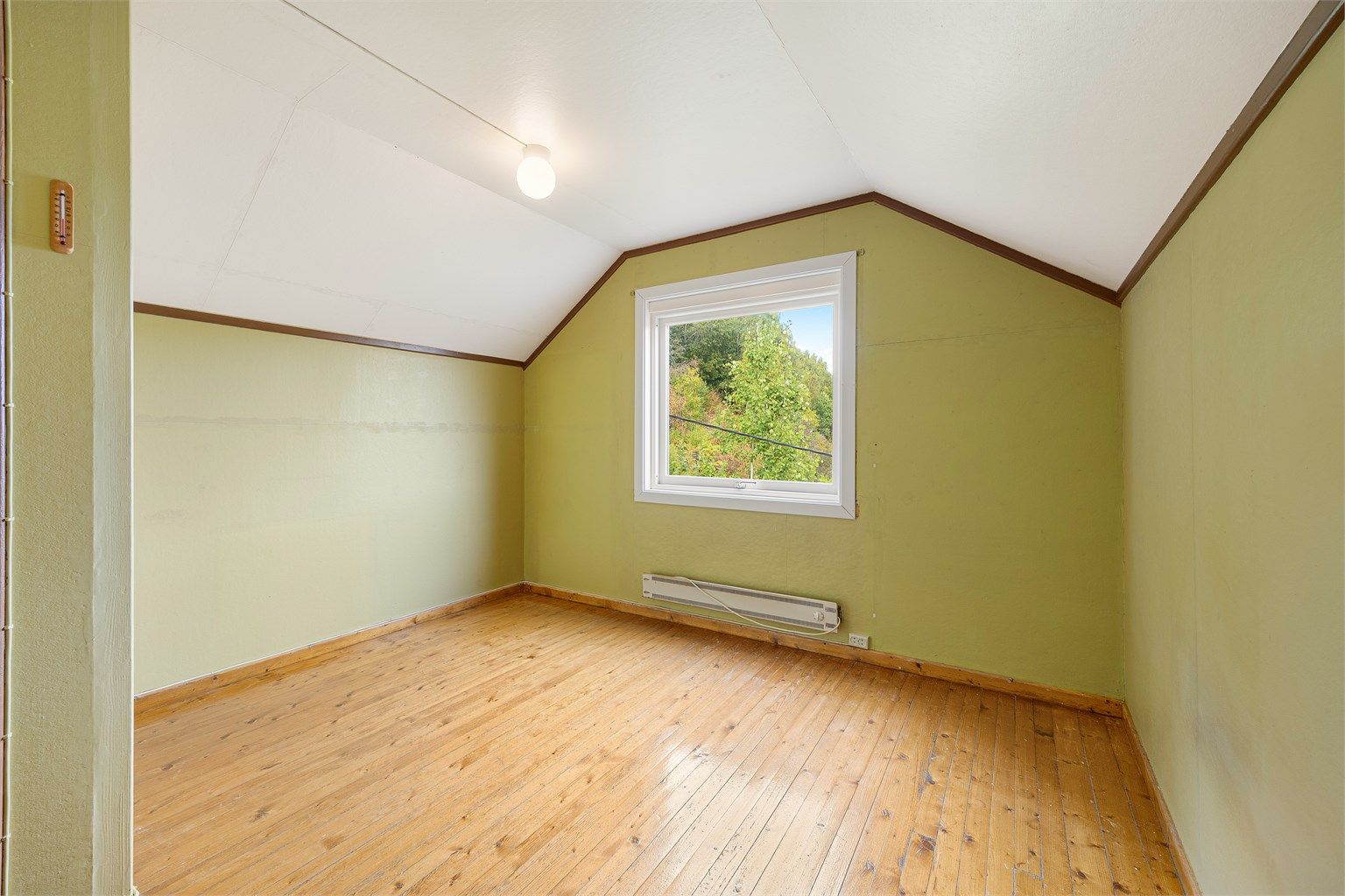 Soverom i loftsetasjen med tregulv og skråtak.