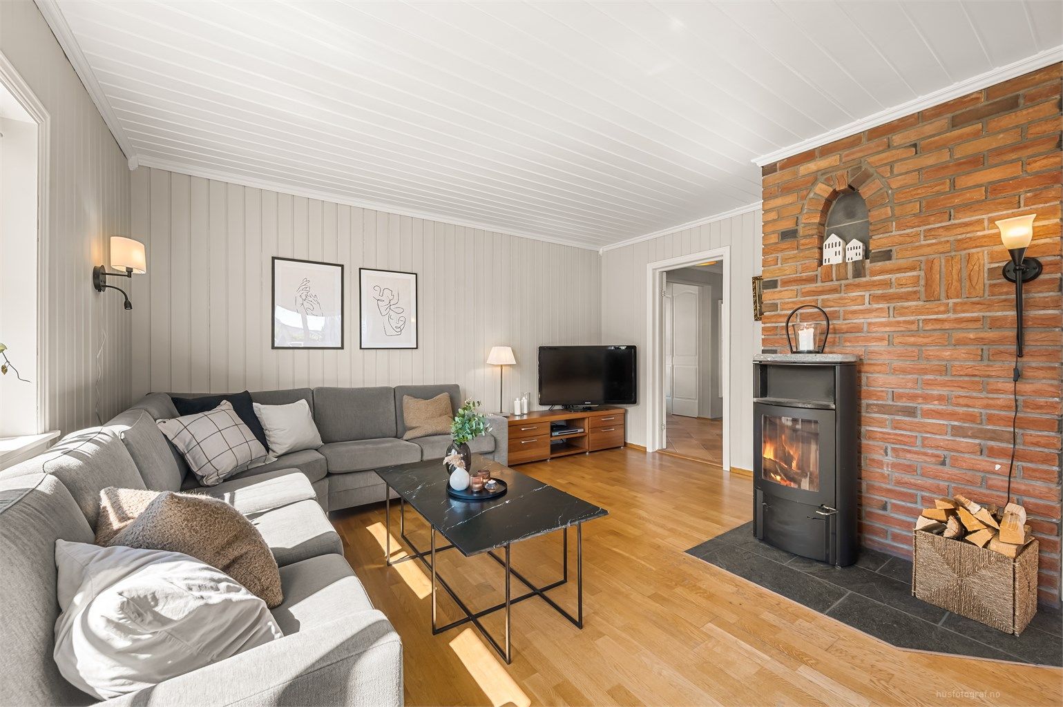 Stue med frittstående peisovn med flislagt gulv og murvegg bak