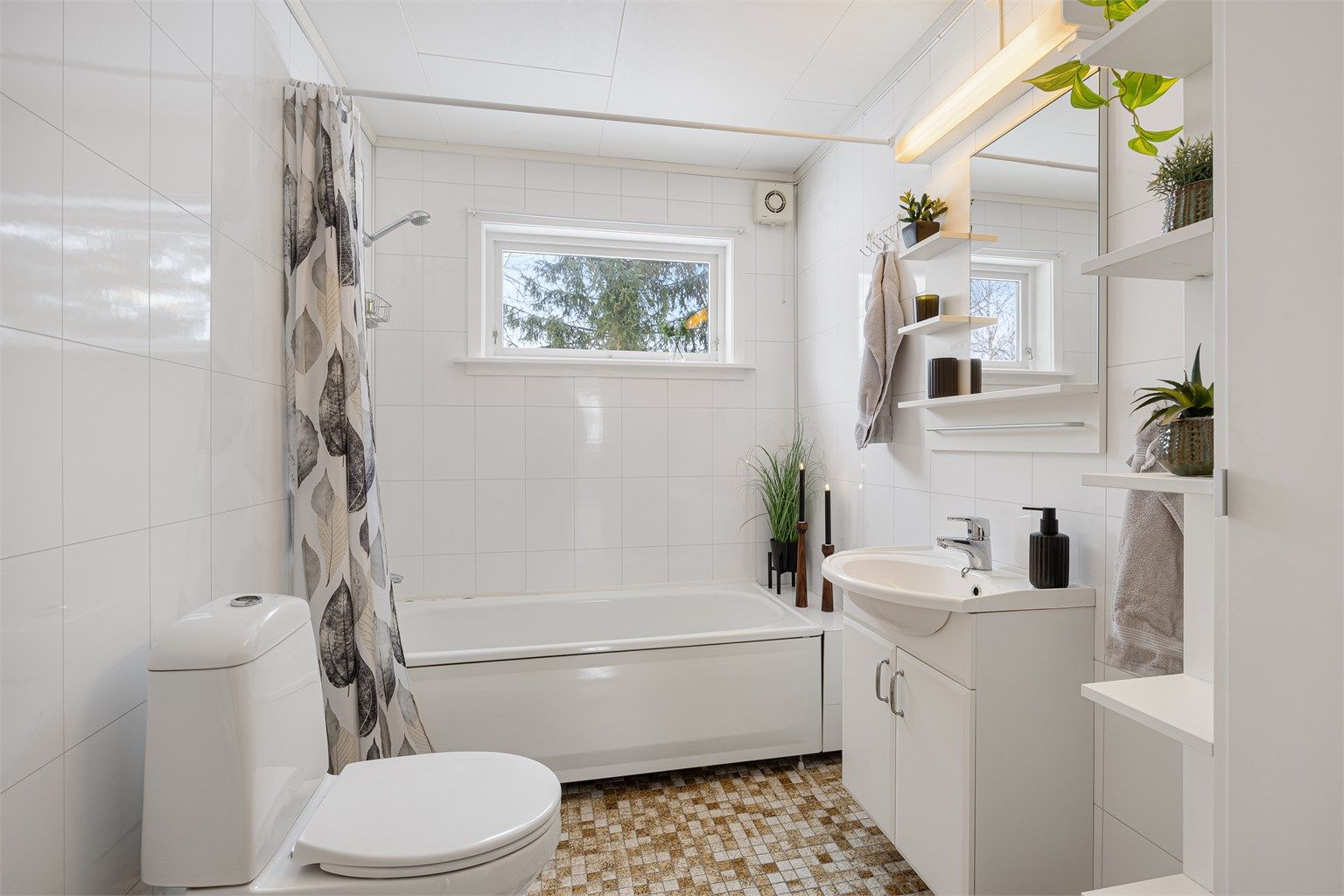 Badet i første etasje har flislagt gulv med elektriske varmekabler og badekar med dusj.