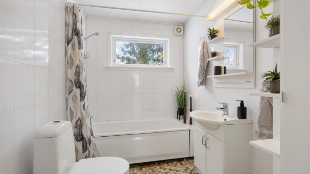 Badet i første etasje har flislagt gulv med elektriske varmekabler og badekar med dusj.