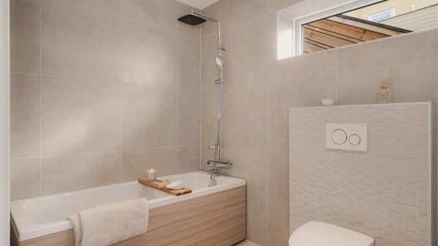 Lekkert baderom som er utstyrt med badekar, regndusj og vegghengt toalett.