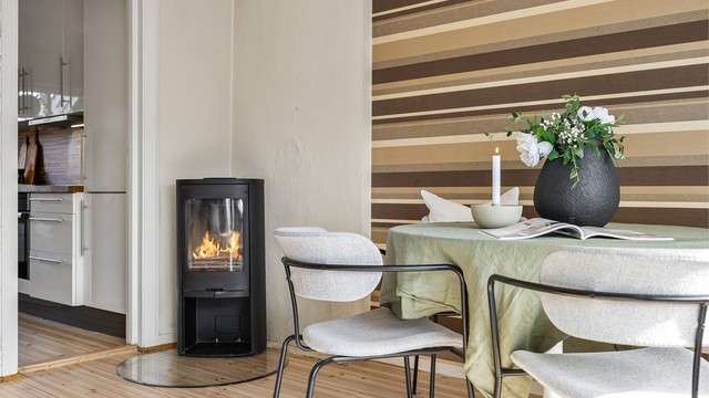 Frittstående peisovn med glassplate på gulv og luft-til-luft varmepumpe i stuen.