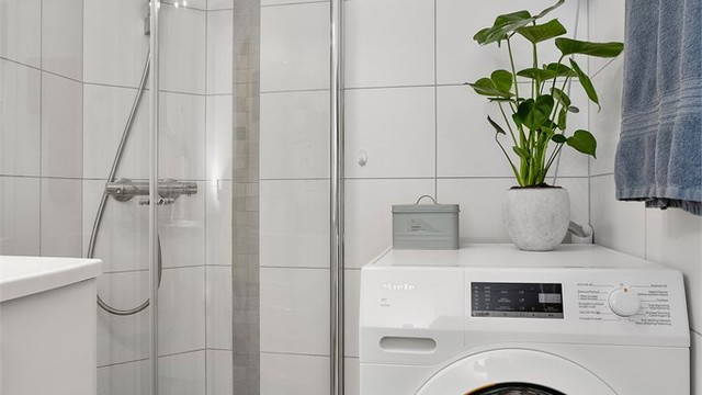 Badet har opplegg for vaskemaskin og en praktisk dusjnisje med buede glassdører.