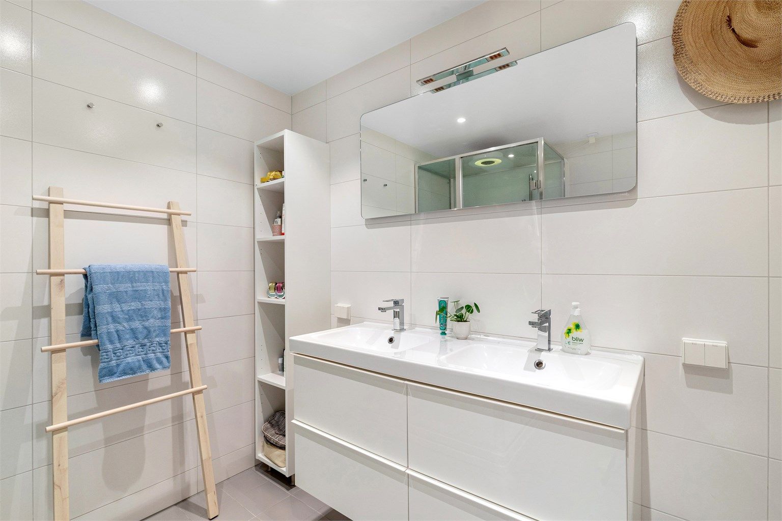 Badet har vegghengt speil med og stikkontakter på vegg over servant. Downlights