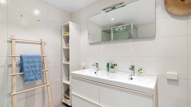 Badet har vegghengt speil med og stikkontakter på vegg over servant. Downlights