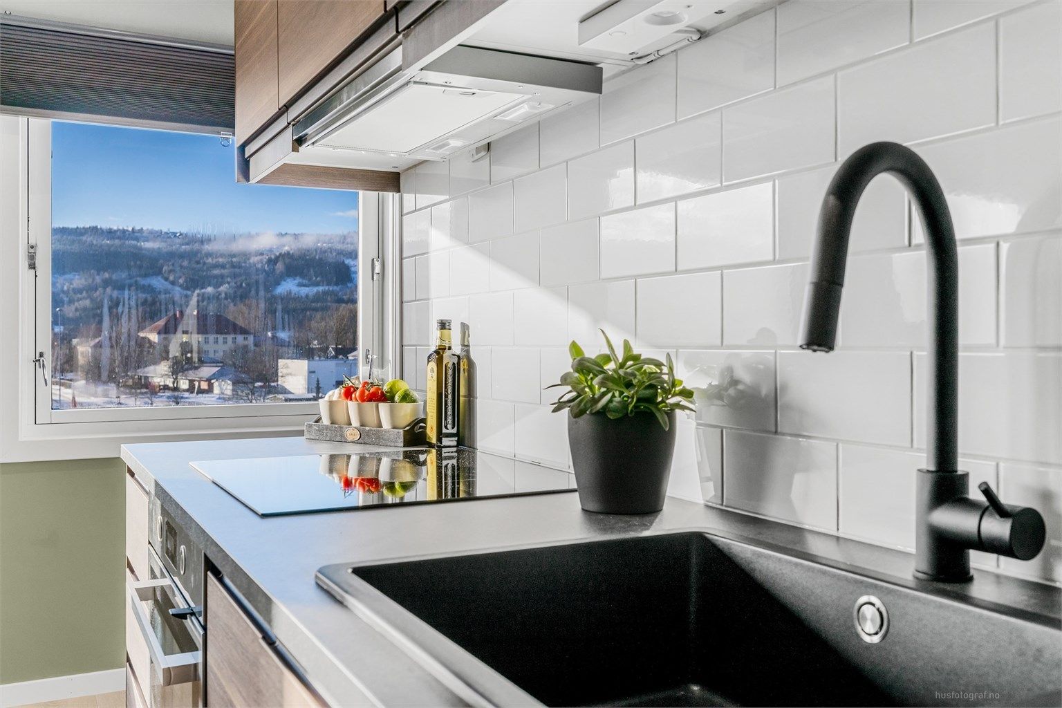 Kjøkkenet har moderne detaljer som sort blandebatteri og integrert platetopp med god arbeidsplass.
