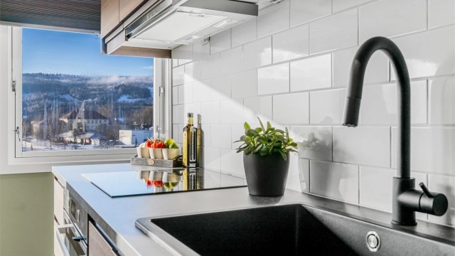 Kjøkkenet har moderne detaljer som sort blandebatteri og integrert platetopp med god arbeidsplass.