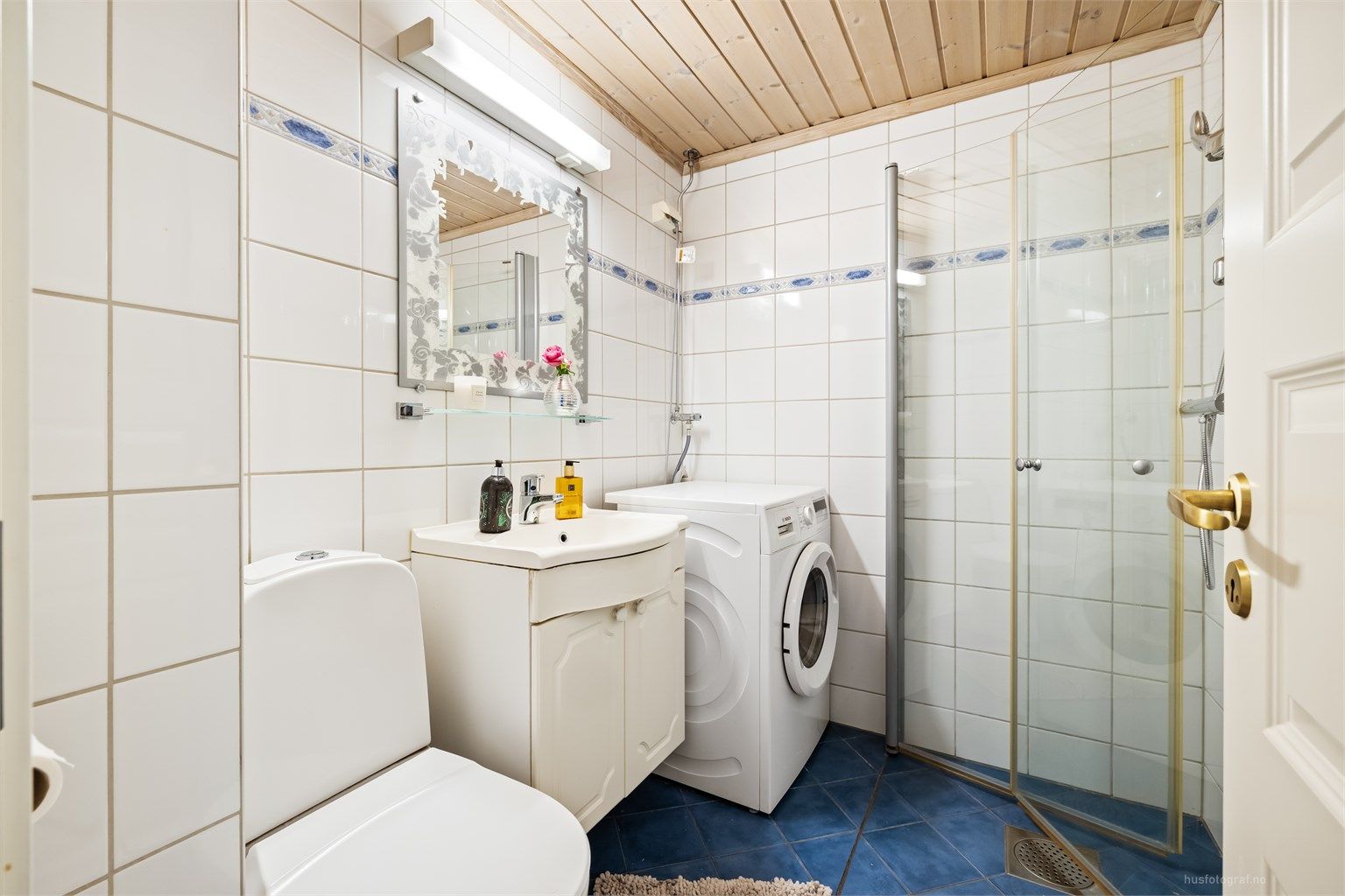 Badet har dusjhjørne med foldedører av glass og gulvvarme.