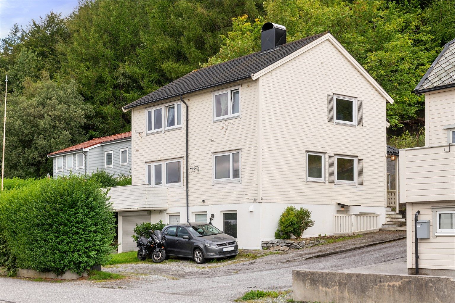 Fasade med enkel adkomst og to tilhørende parkeringsplasser. 