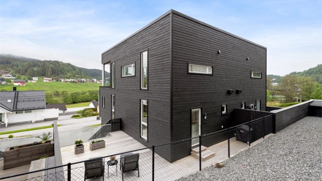 Fasade og terrasse mot nordøst. Stor terrasse på terreng med levegg mot naboer samt trapp til gårdsplass