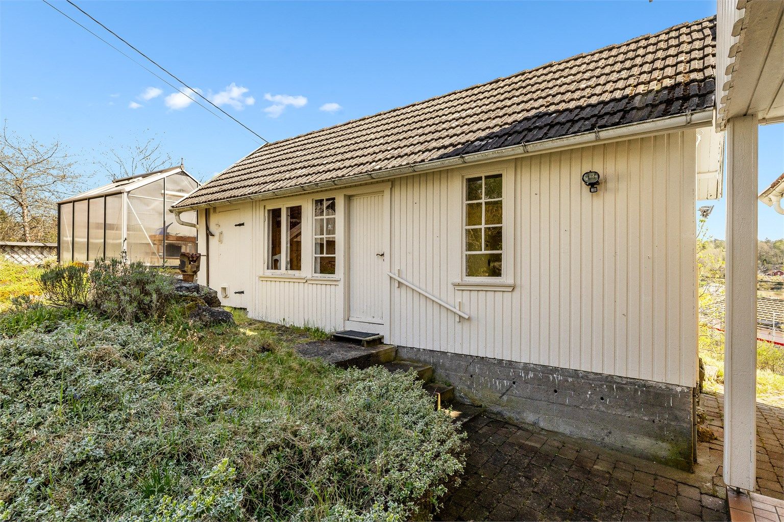 Koselig bryggerhus/anneks. Her er det behov for oppgradering. Drivhuset kan gjøre deg selvforsynt med grønnsaker. Kjekt når man er øyboer.