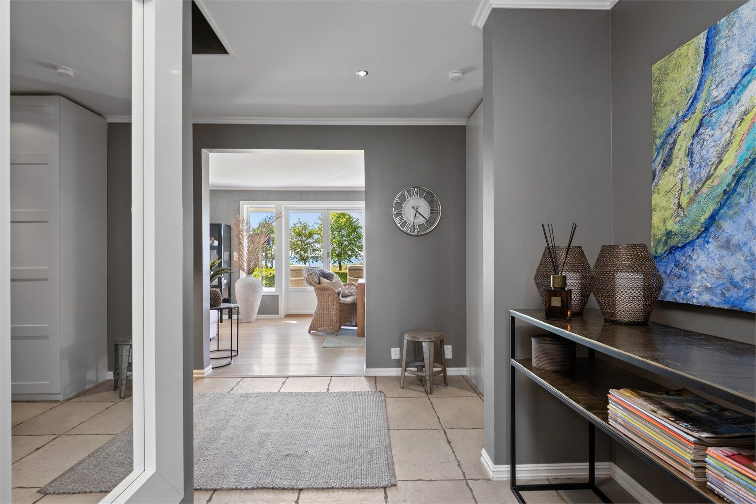 Entreen glir sømløst over i en hall med downlights i taket, innredet med samme type skap og overflater.