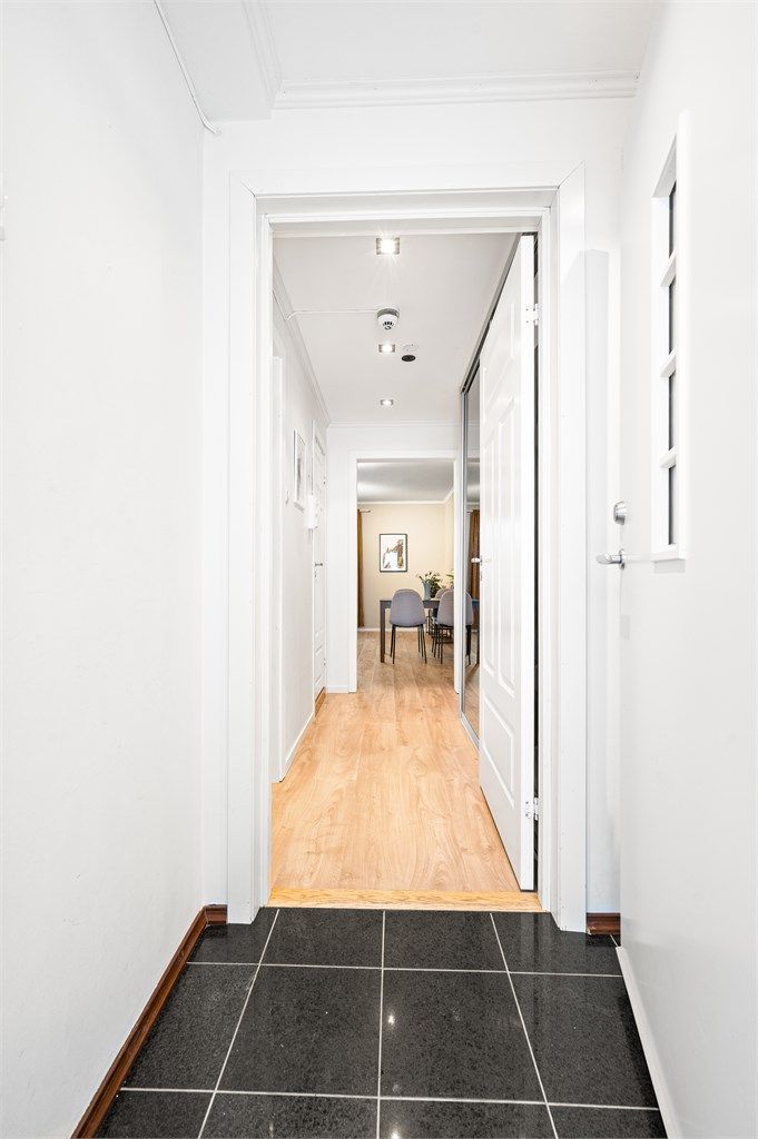 Entréen har flislagt gulv med elektrisk gulvvarme og leder deg videre inn i leiligheten.