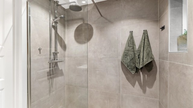 Badet er innredet med vegghengt klosett, servant med underskap, speilskap og dusjhjørne med fast glassvegg