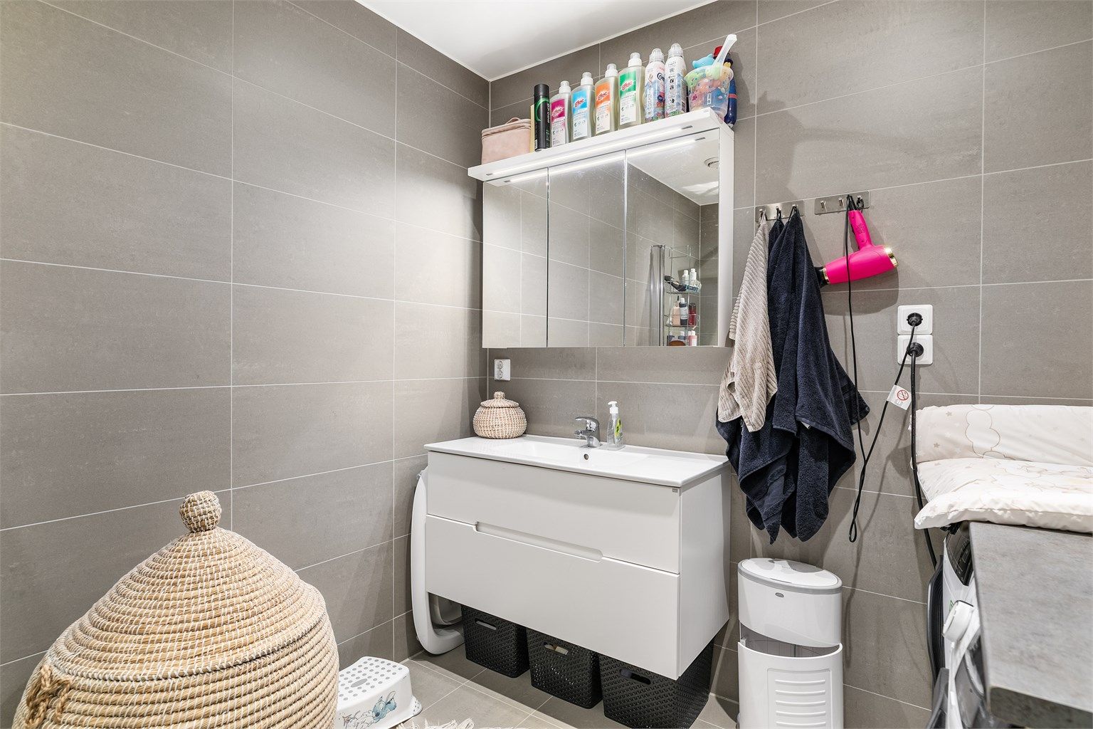 Grå fliser på både gulv og vegger gir badet helhet. I gulvet er det elektrisk varme.