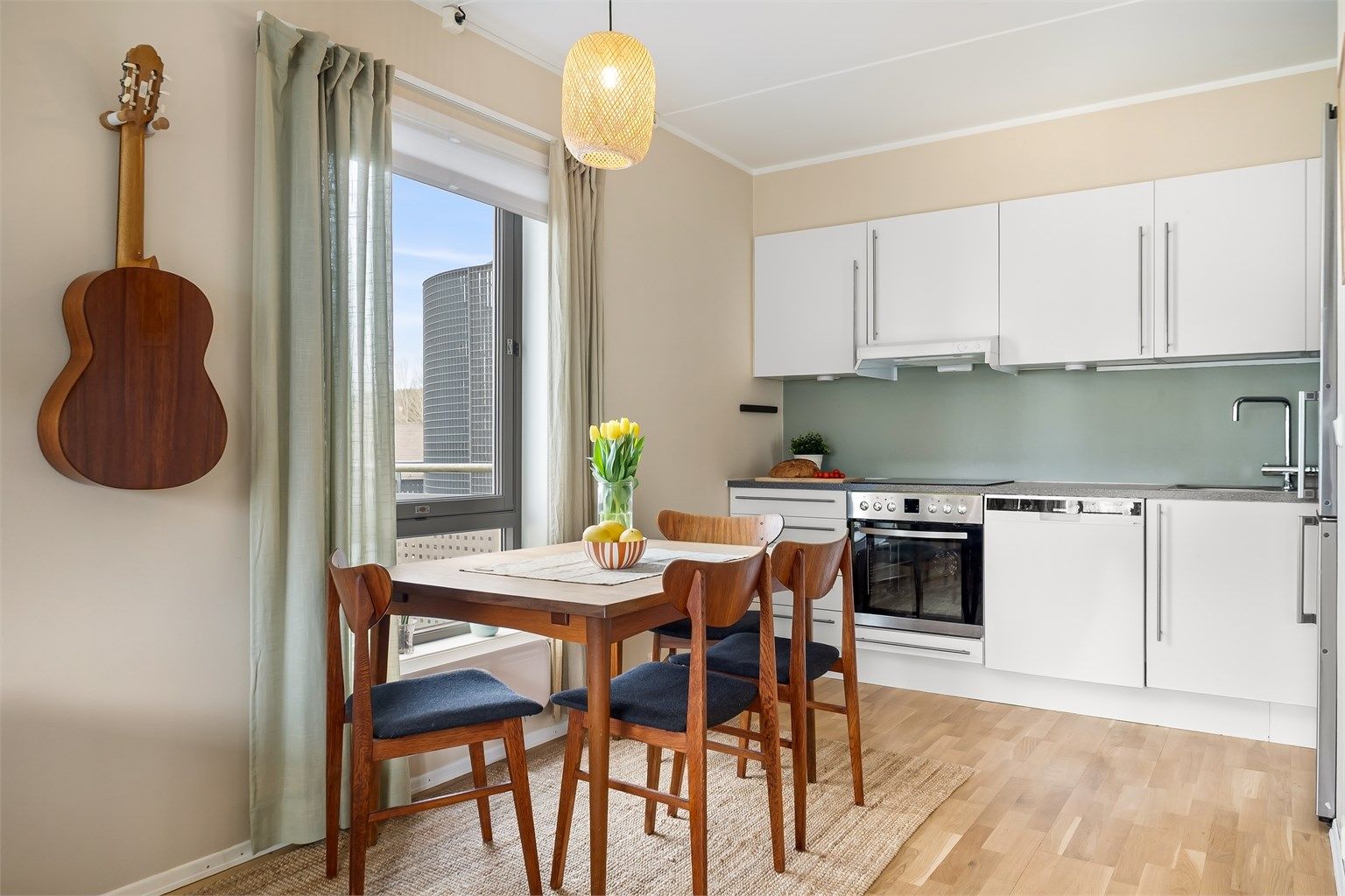 Kjøkkeninnredning med glatte, hvite fronter og laminatbenkeplate. Frittstående kjøleskap med fryser medfølger handelen, på lik linje med integrerte hvitevarer.