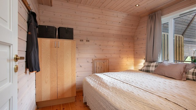 Soverom i 3. etasje med panelkledde vegger, furugulv og garderobeskap.