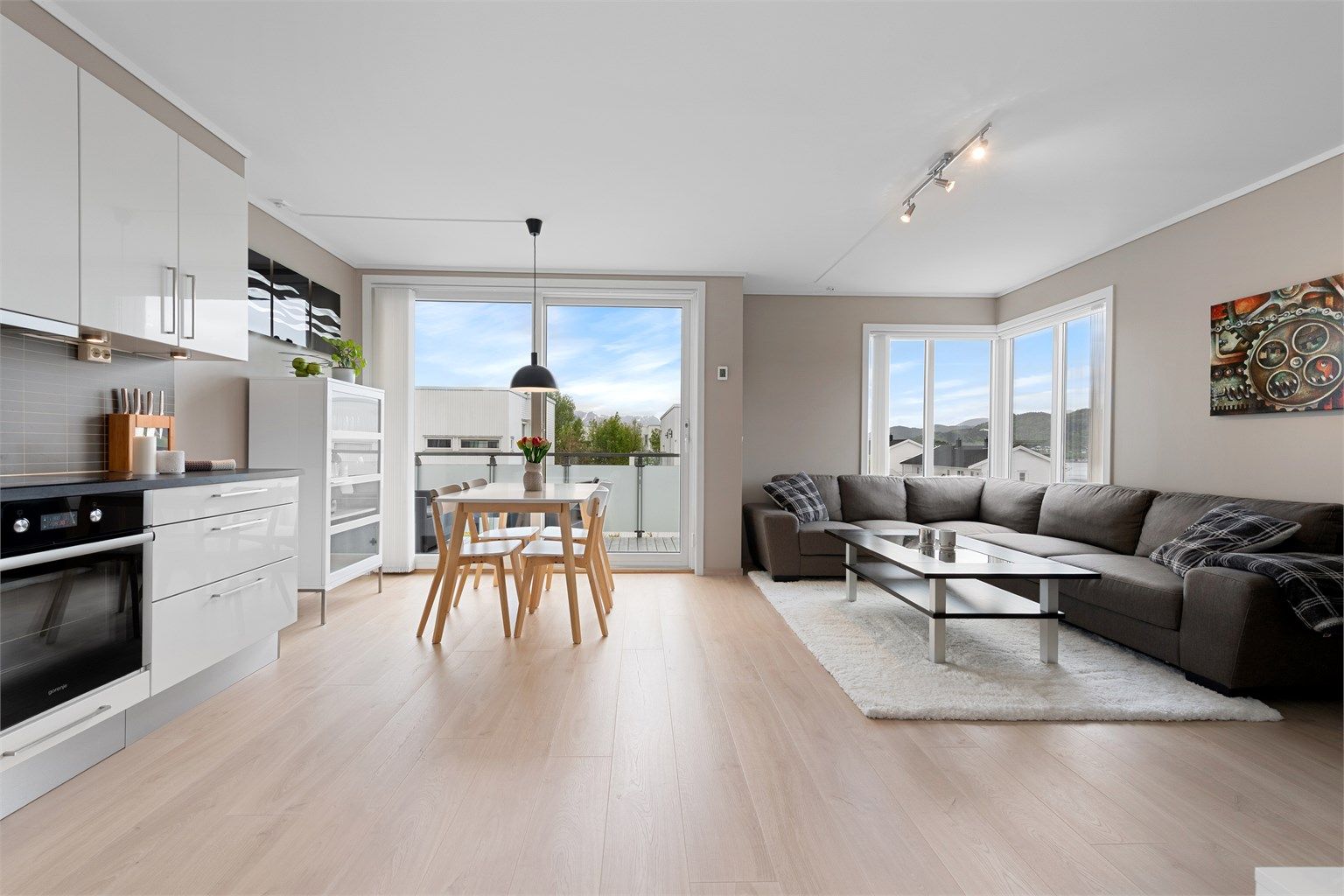 Stue og kjøkken i åpen løsning med gode lysforhold fra store vindusflater