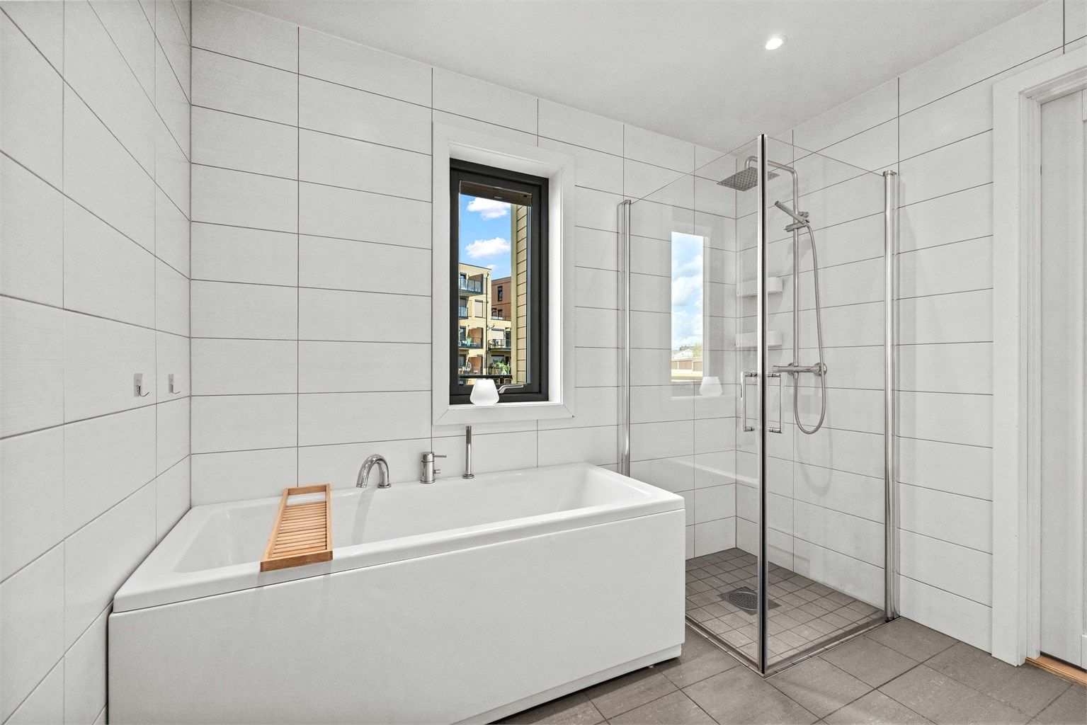 Badet er utstyrt med både badekar og et separat dusjhjørne med glassdører.