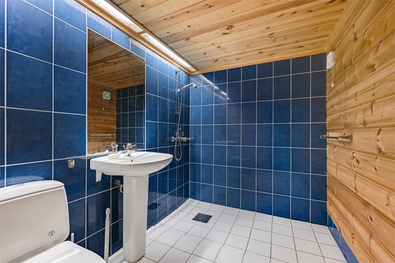 Funksjonelt baderom i kjelleretasjen med fliser på gulv, toalett og servant. (Ikke godkjent til varig opphold)