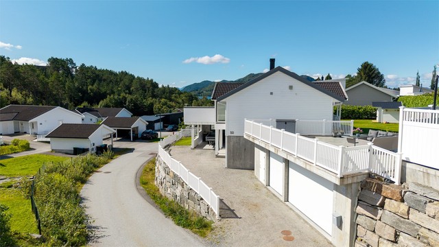 Eiendommen ligger i rolige omgivelser med romslig gruset gårdsplass foran garasje og carport.