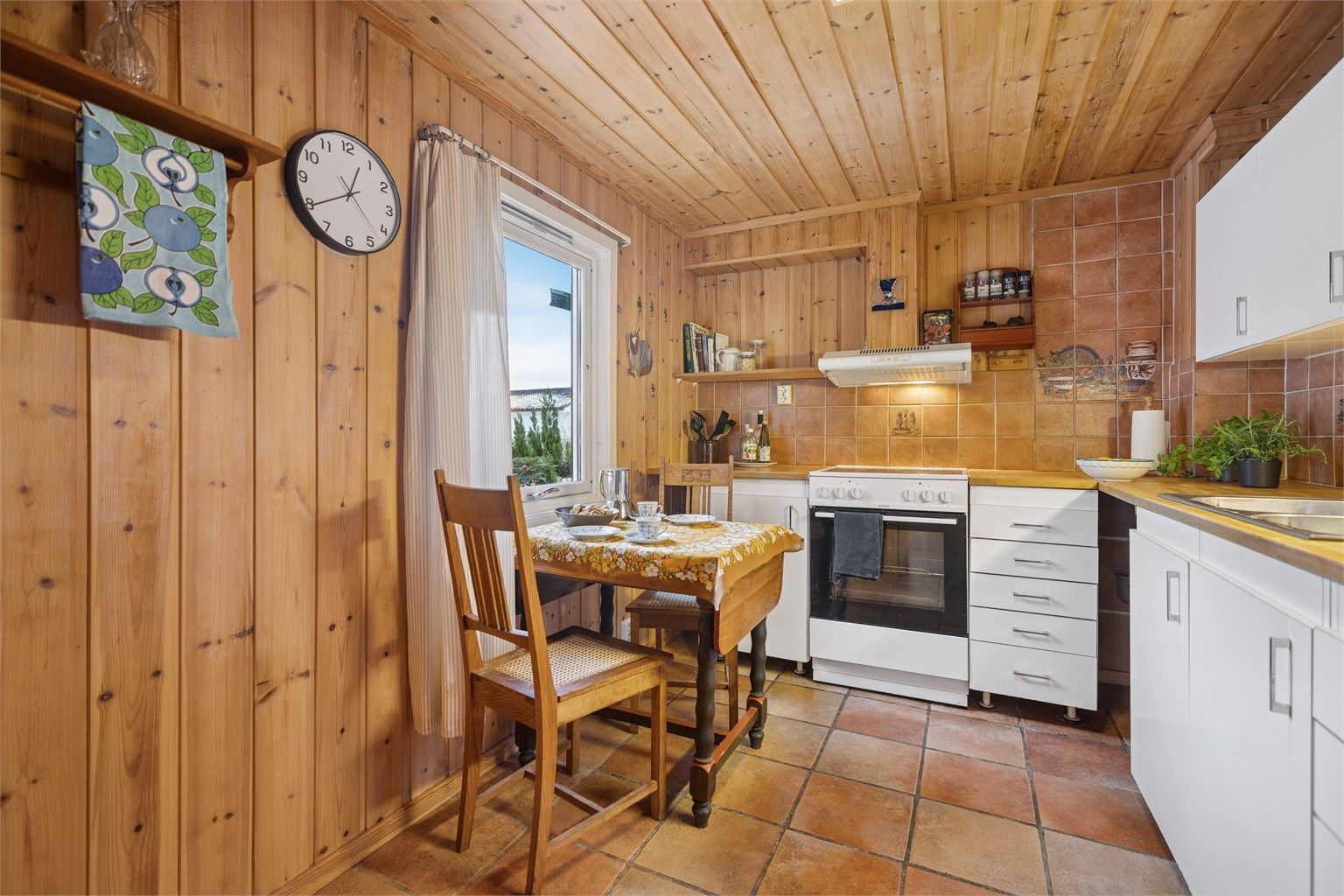 Kjøkkenet har flislagt gulv med gulvvarme og en lys innredning med slette fronter. 