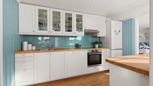 Moderne kjøkkeninnredning med glass i sprutsonen mellom benk og overskap.