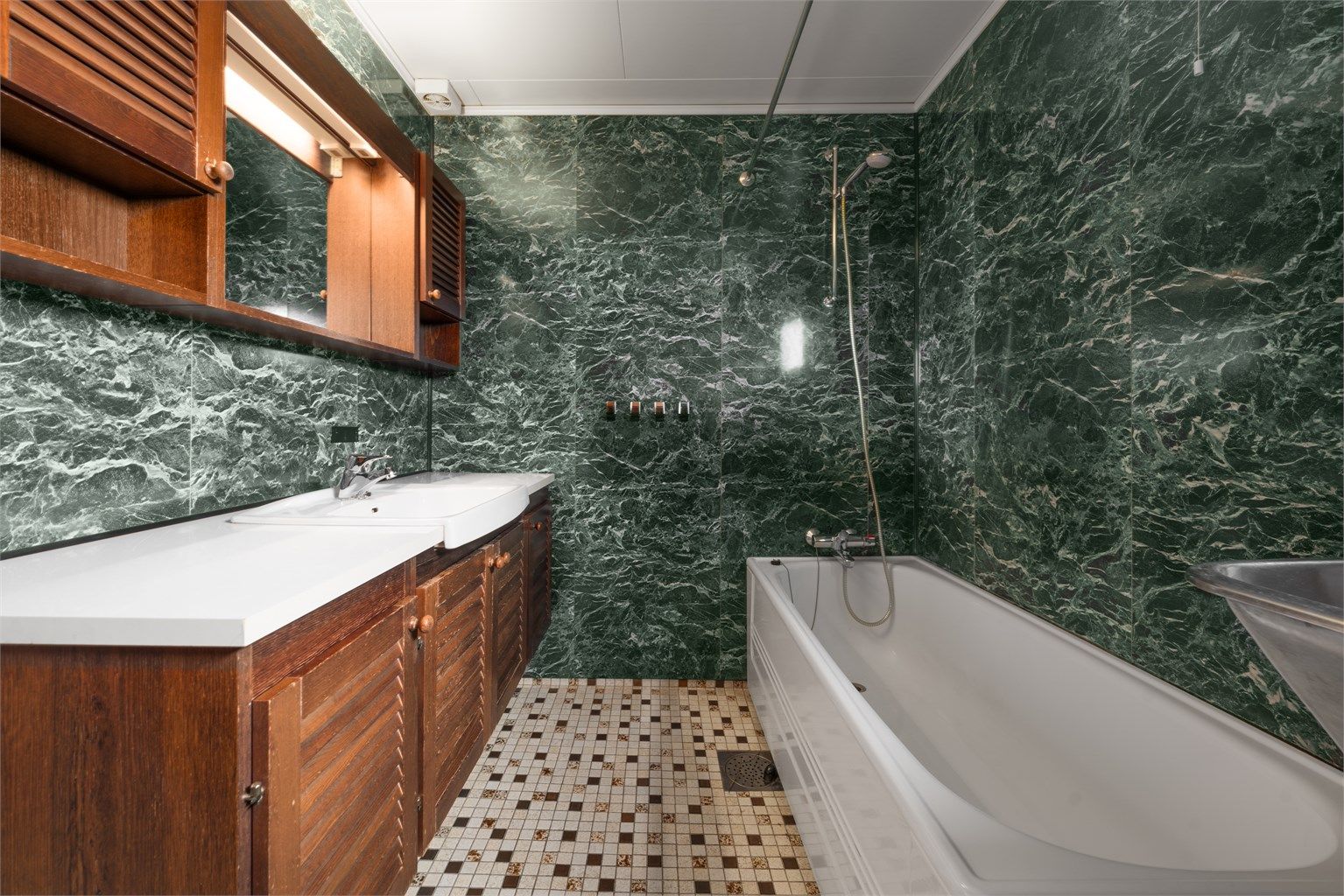 Baderomsinnredning med nedfelt servant og overskap med speil og belysning.