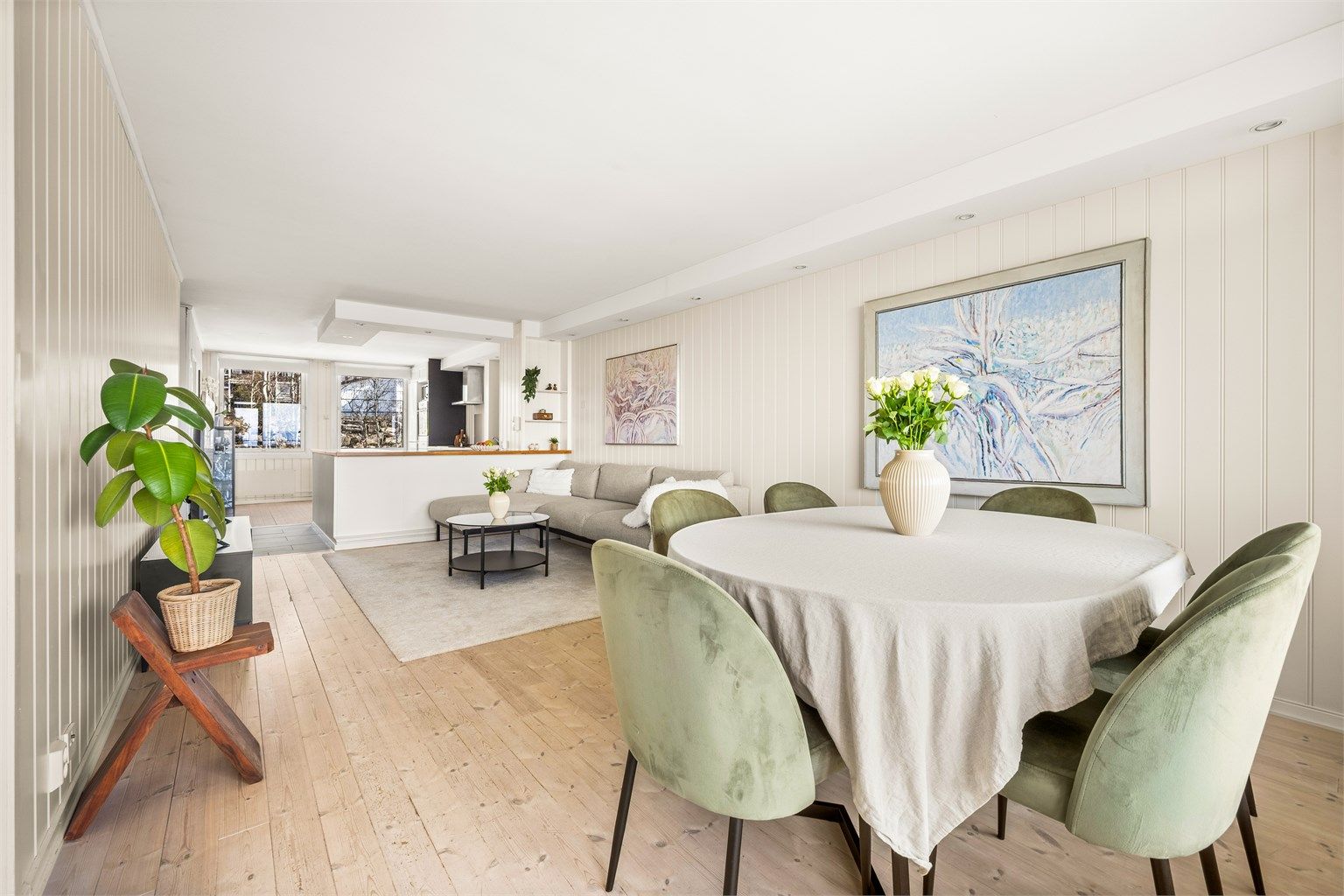 Den åpne løsningen mellom stue og kjøkken skaper en sosial og luftig atmosfære. 