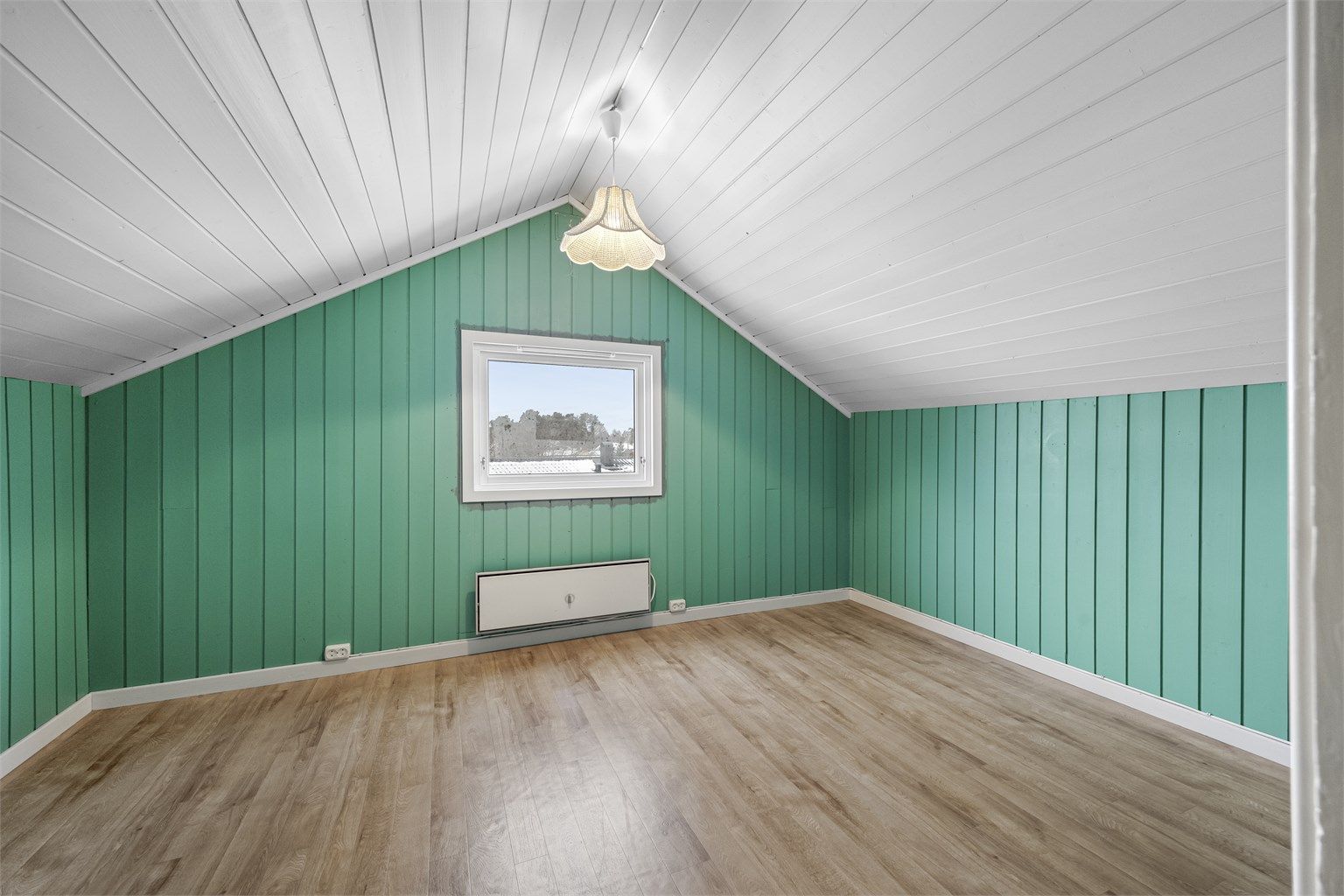 Det ene av to innredede rom på loftet, med panel på vegger og i skråtak.