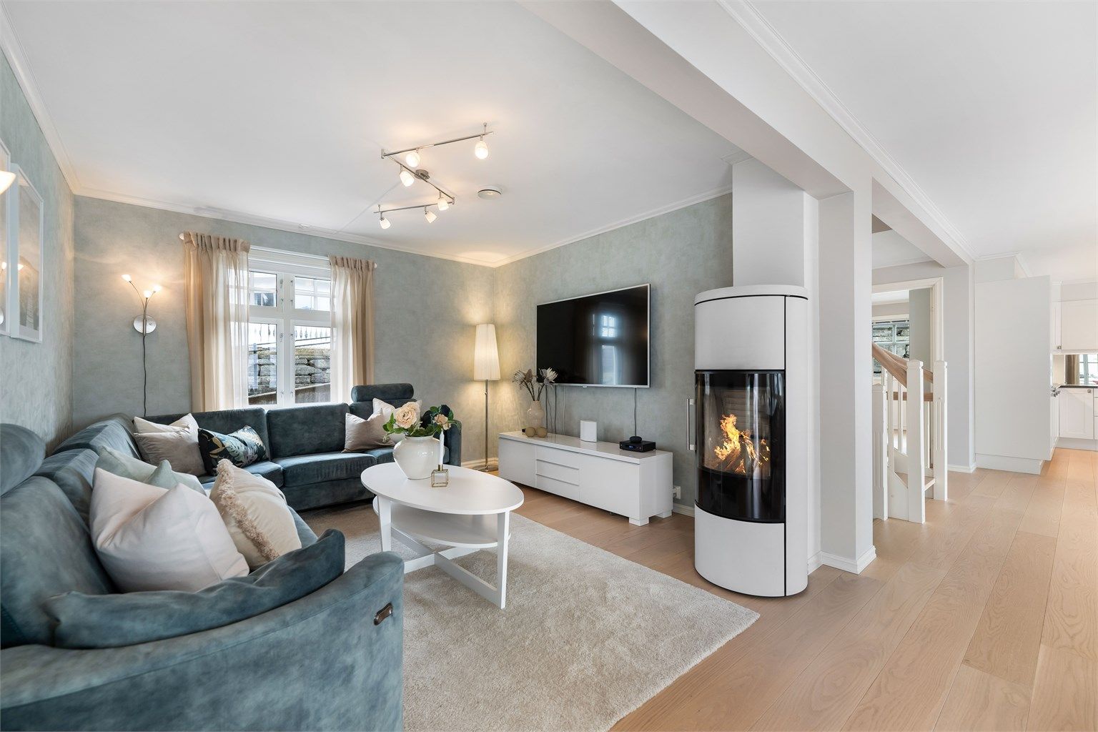 Sammen med den varme tonen i gulvet bidrar den stilfulle peisovnen til å skape en lun og innbydende atmosfære