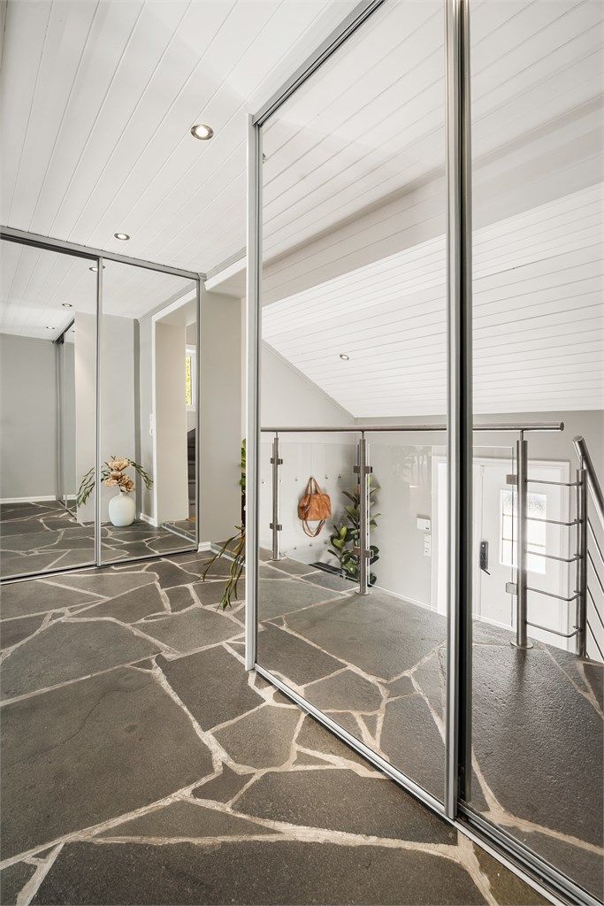 Hall med skyvedørsgarderober som har speilfronter.