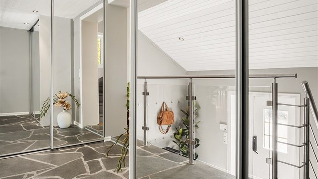 Hall med skyvedørsgarderober som har speilfronter.