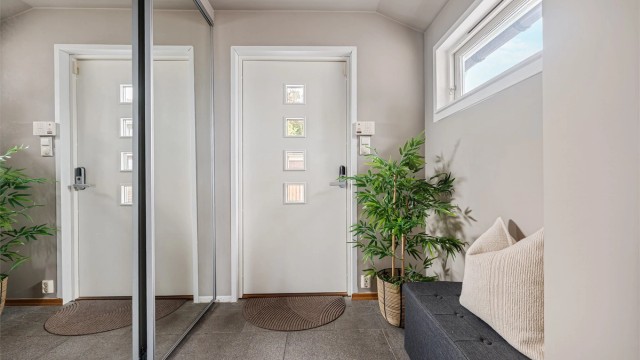 Entré med fliser og parkett på gulv, varmekabler og malte vegger. Ved entré ligger soverom I og bad I.