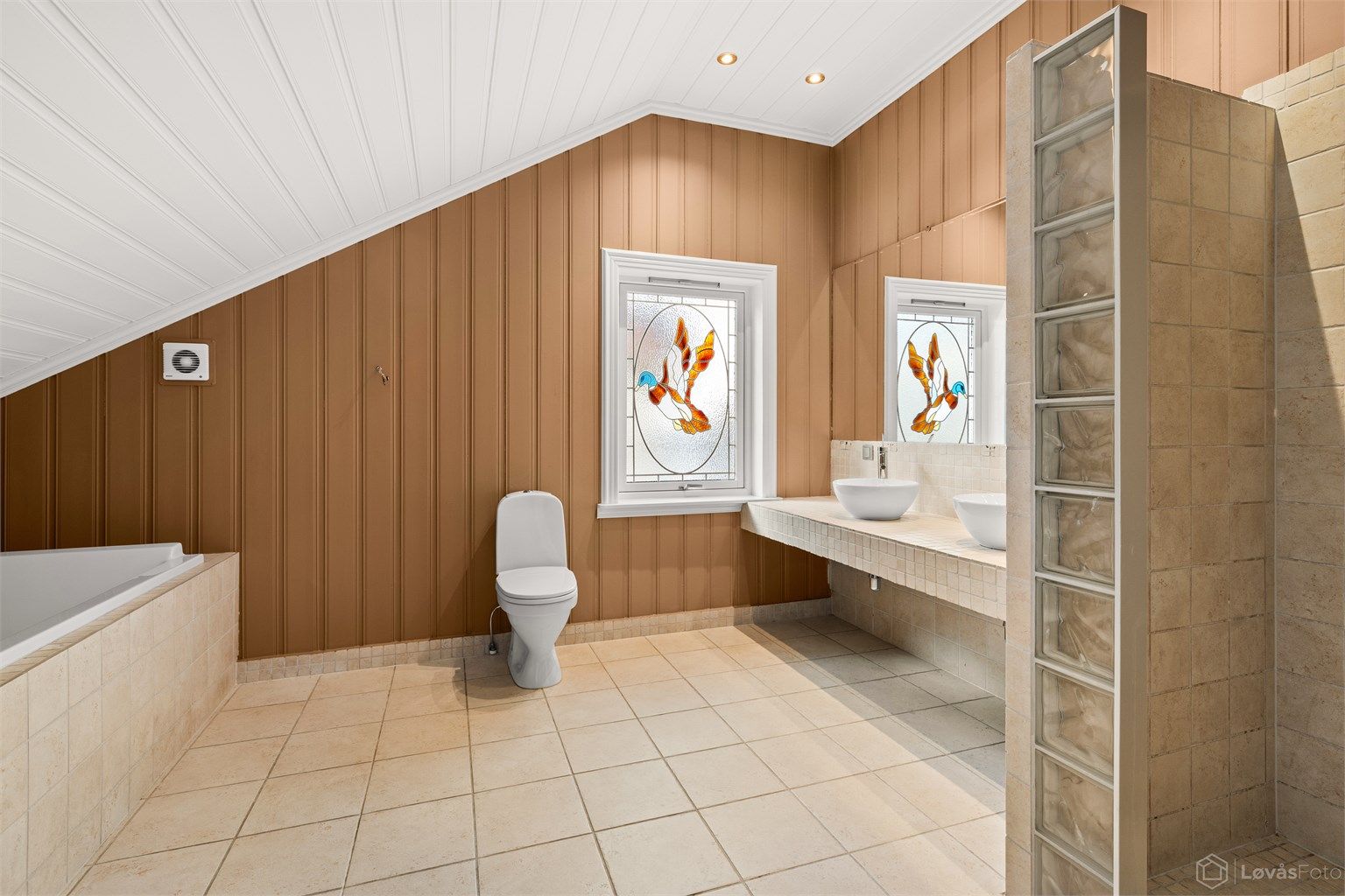 Det romslige badet i andre etasje har gulvvarme, doble servanter og et sjarmerende vindu med glasskunst.