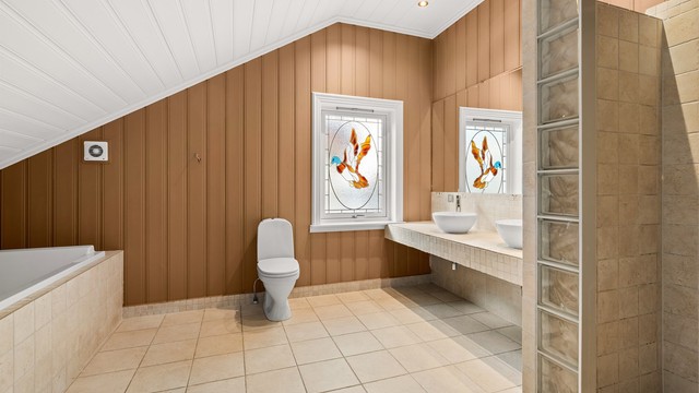 Det romslige badet i andre etasje har gulvvarme, doble servanter og et sjarmerende vindu med glasskunst.