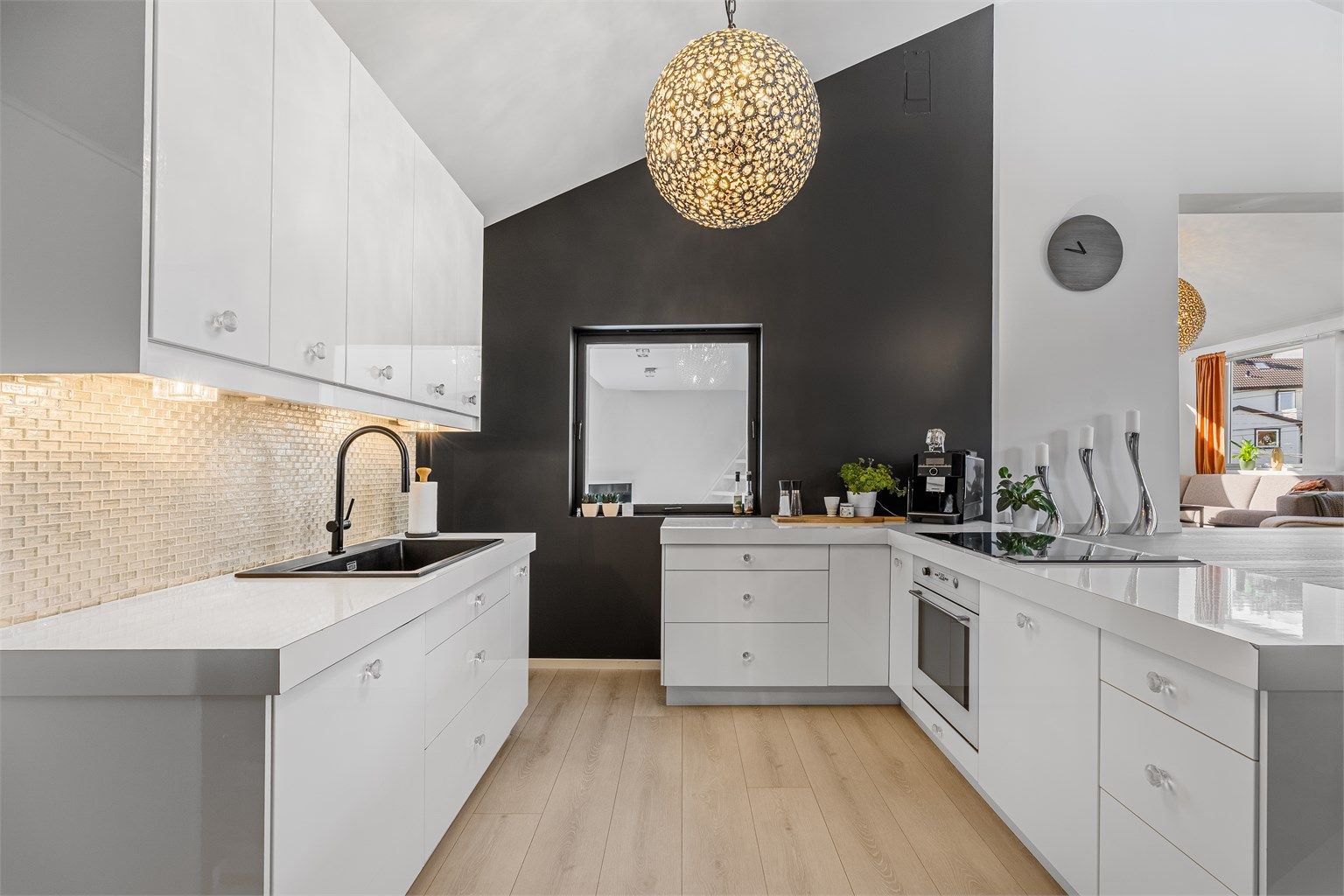 Det er en åpen kjøkken/stue løsning. Kjøkkenet er minimalistisk med hvite slette fronter. 