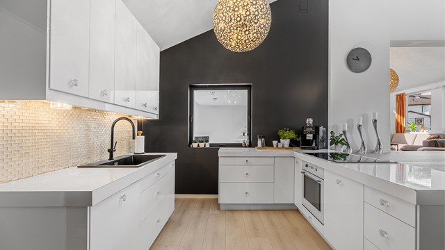 Det er en åpen kjøkken/stue løsning. Kjøkkenet er minimalistisk med hvite slette fronter.