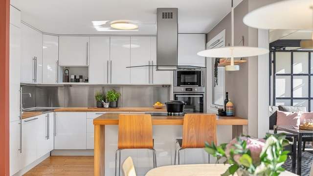 Kjøkkenet fra IKEA har glatte høyglansfronter og benkeplate i heltre med barløsning.
