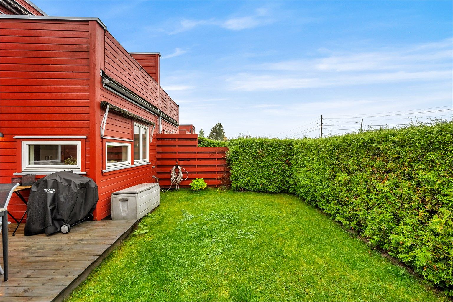 Til boligen hører også en frodig gressplen omkranset av tett hekk, som gir en skjermet og trygg plass for lek og avkobling.