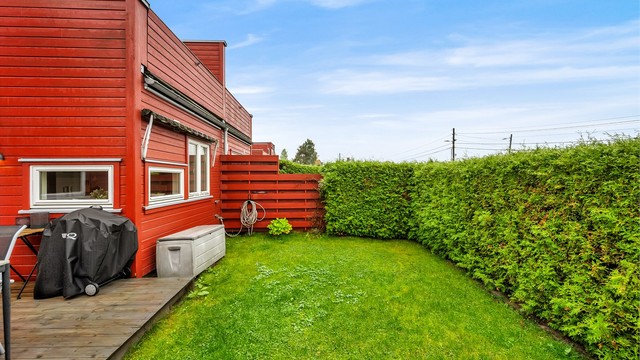 Til boligen hører også en frodig gressplen omkranset av tett hekk, som gir en skjermet og trygg plass for lek og avkobling.