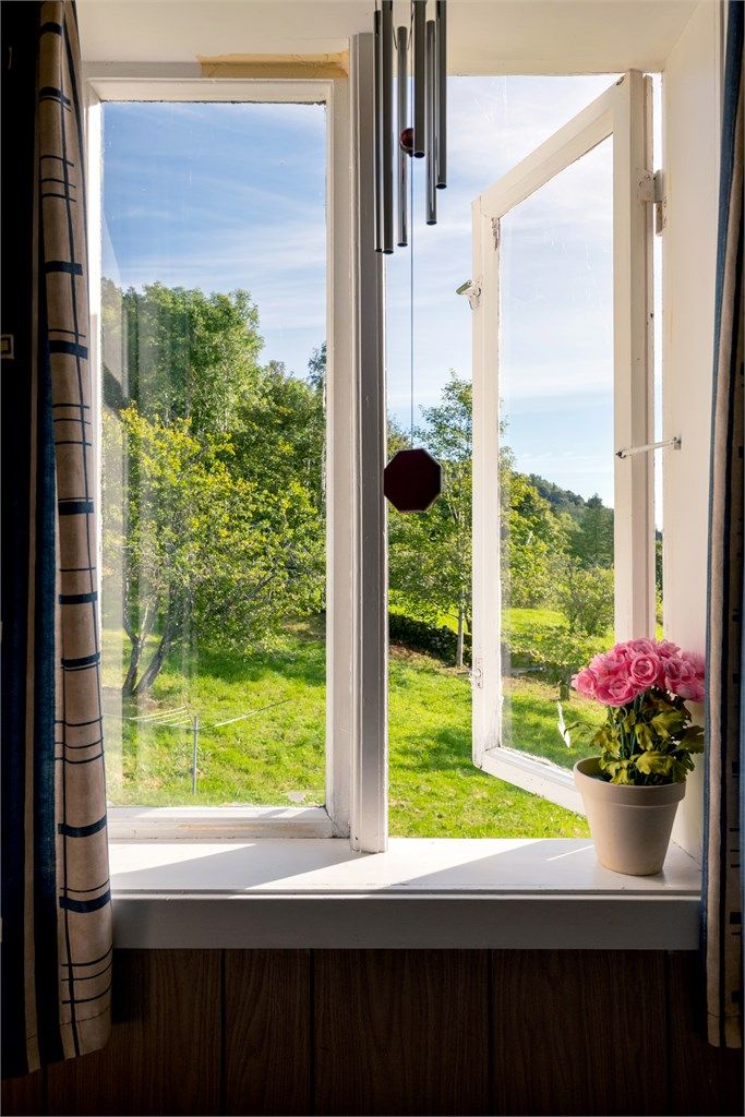 Utsyn fra loftsvinduet mot de grønne engene og åssiden bak boligen.