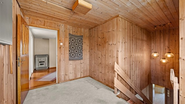Trapperom og gang i andre etasje med panelkledde vegger.