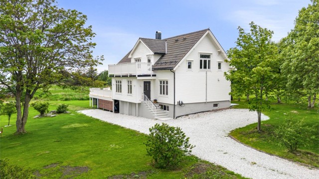 Stor, opparbeidet tomt med plenarealer og gruset biloppstillingsplass
