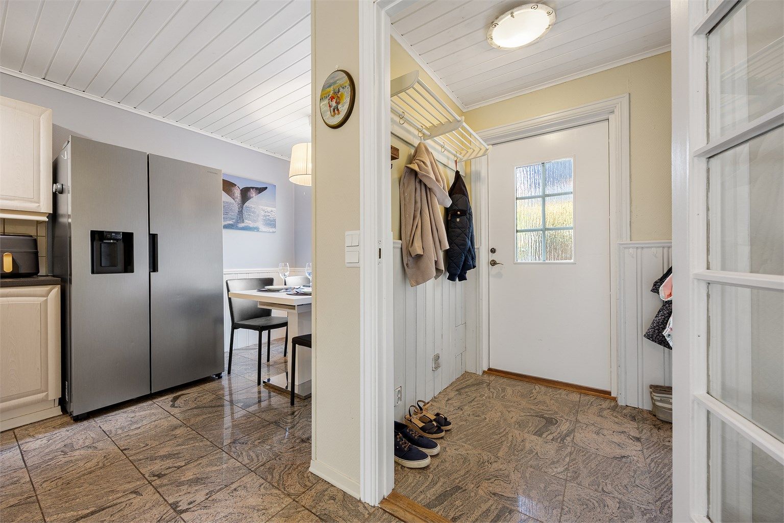 Kjøkkenet har åpen passasje mot gangen og plass til spisebord ved vinduet.